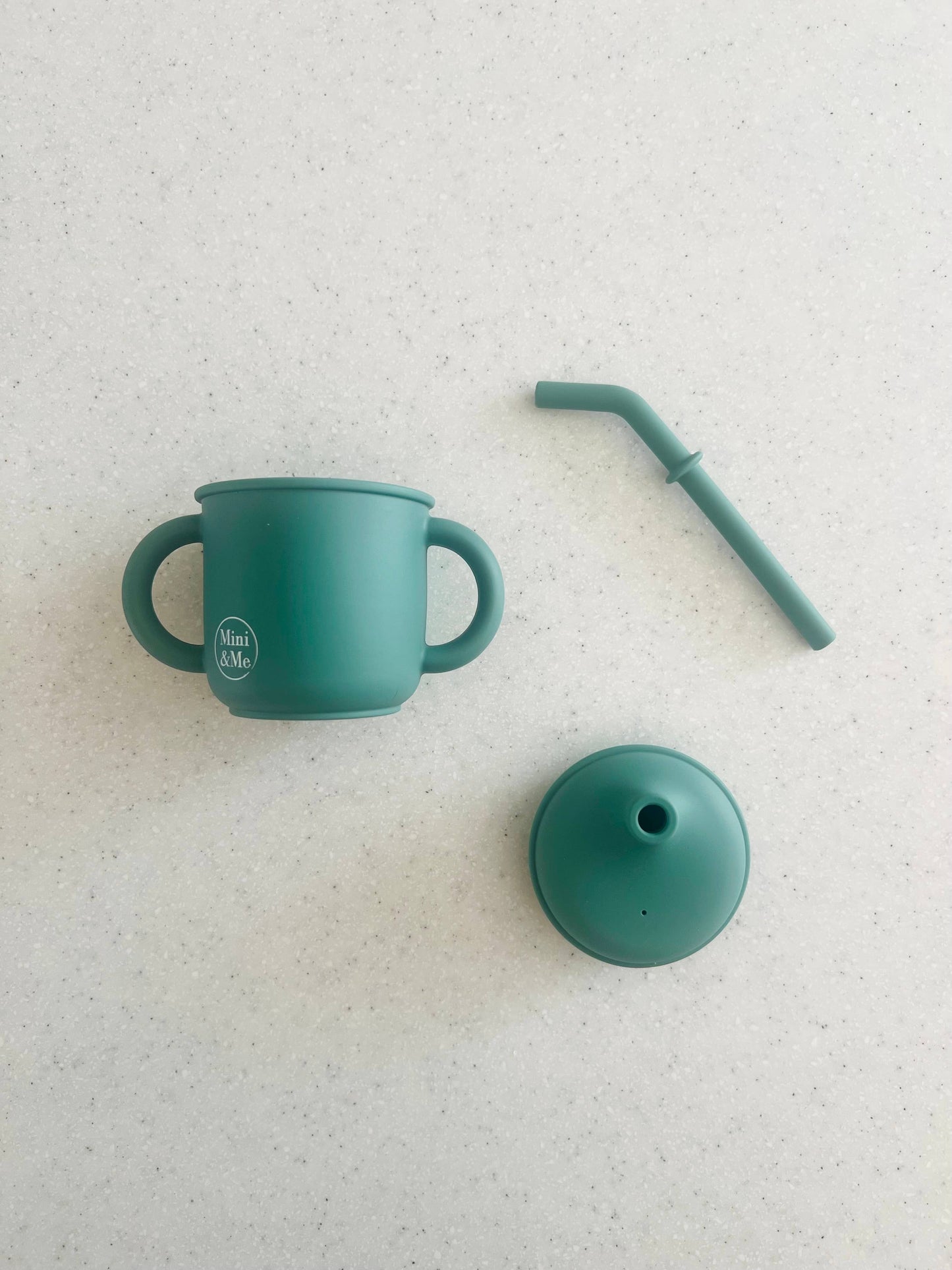 The Mini & Me Transitional Straw Sippy Cup Kale in almond, ice-blue and kale-green styled beautifully on a shelf in a chil...