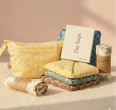 Product set with yellow pouch, folded items, and a book titled 'Tiny Steps' on a beige background.