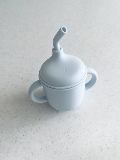 The Mini & Me Transitional Straw Sippy Cup Ice Blue in almond, ice-blue and kale-green styled beautifully on a shelf in a ...