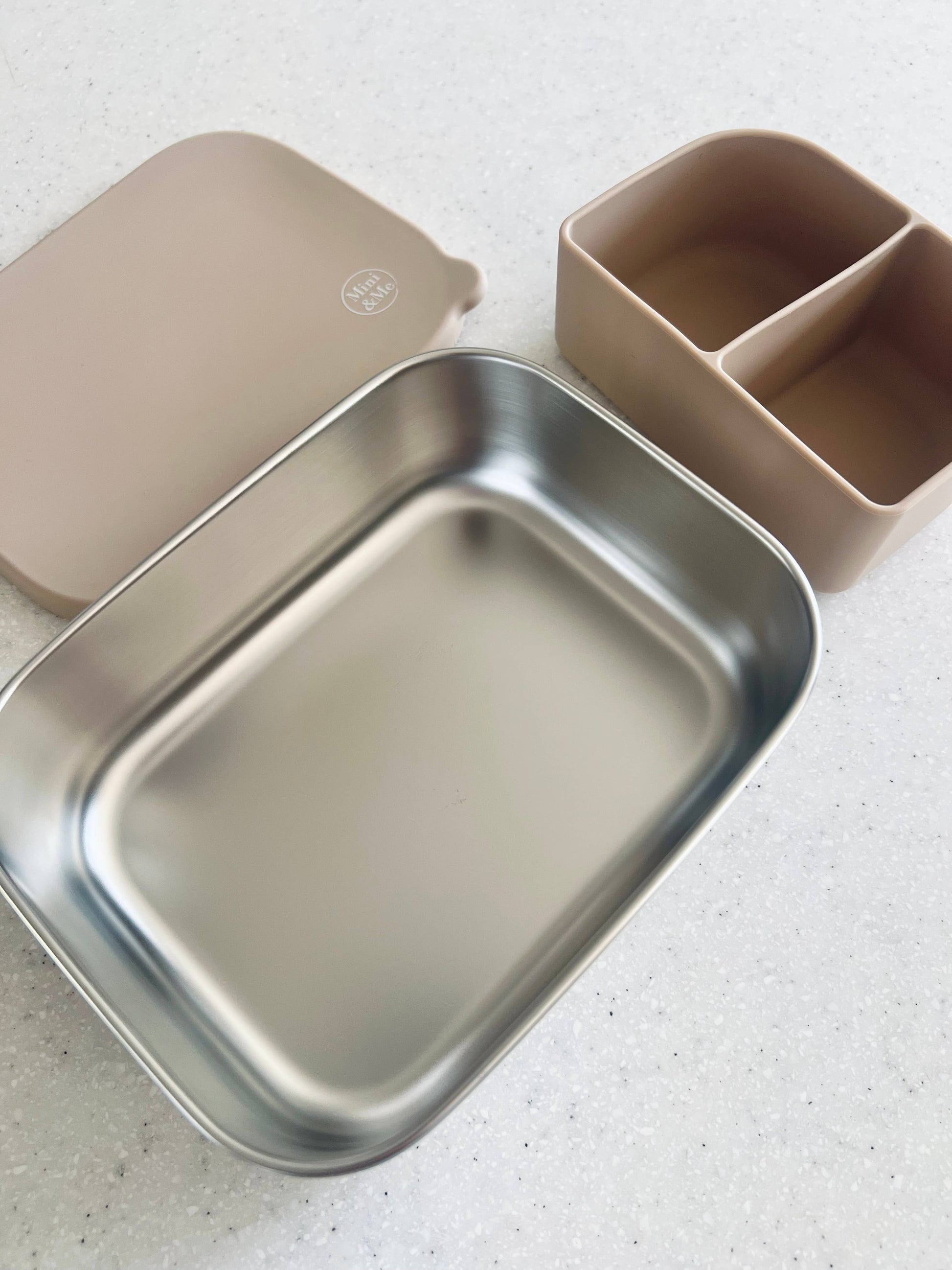 The Stainless Steel Bento Box with Silicone Divider Almond in beige, animal and brown styled beautifully on a shelf in a c...