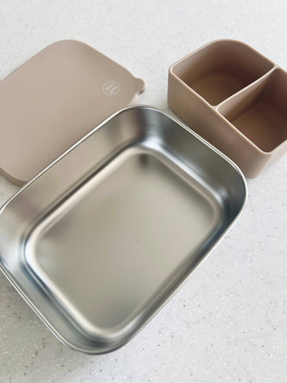 The Stainless Steel Bento Box with Silicone Divider Almond in beige, animal and brown styled beautifully on a shelf in a c...