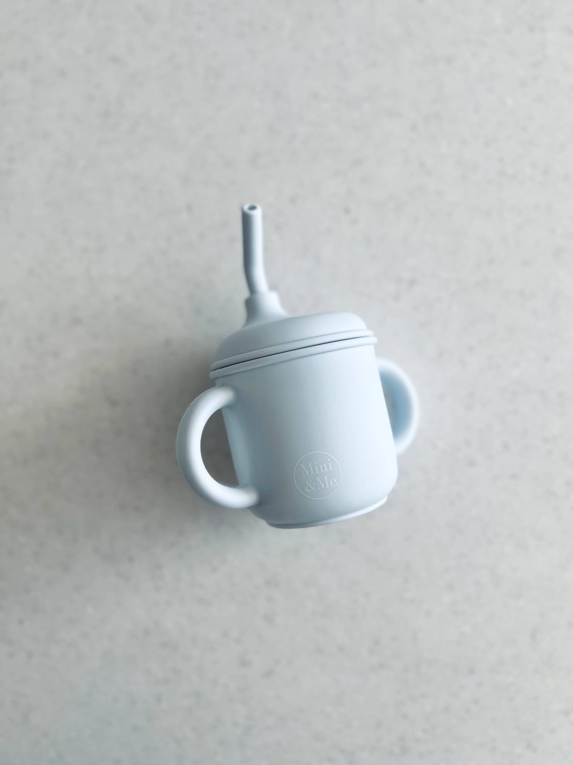 A beautiful lifestyle shot of Mini & Me Transitional Straw Sippy Cup Ice Blue in almond, ice-blue and kale-green by Cuddle...