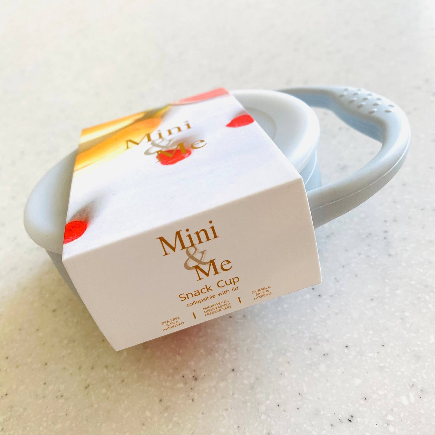 A beautiful lifestyle shot of Mini & Me Snack Cup Collapsible with Lid in almond, ice-blue, kale-green, blue, white, beige...