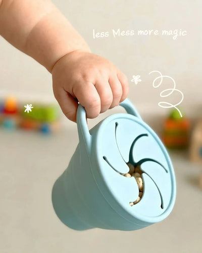 Baby hand holding a Tiny Moments Co snack cup — perfect for little ones learning to self-feed