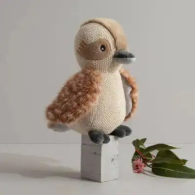 Knitted toy duck on a wooden block with a minimal background