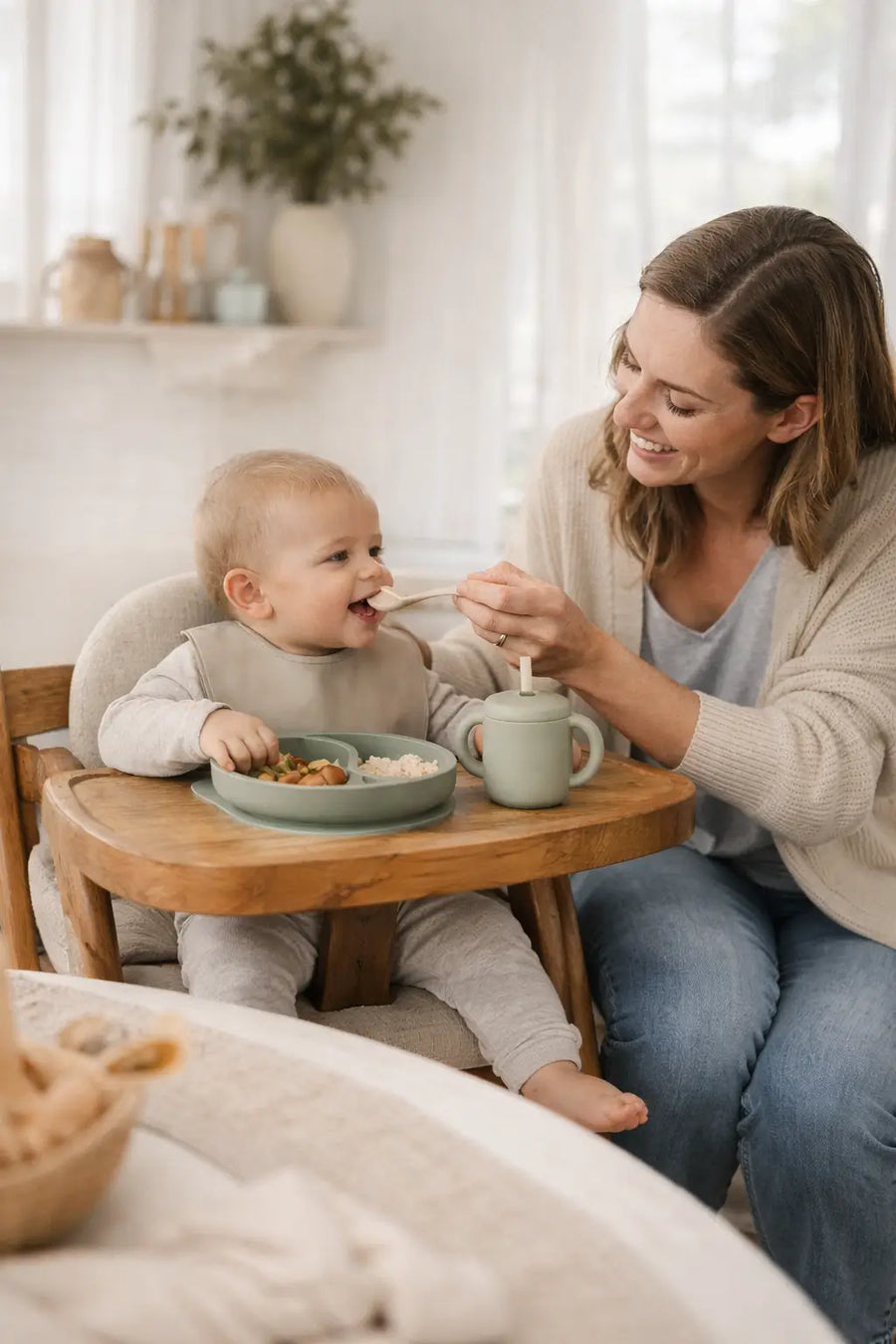 Mum feeding baby in highchair using silicone feeding products