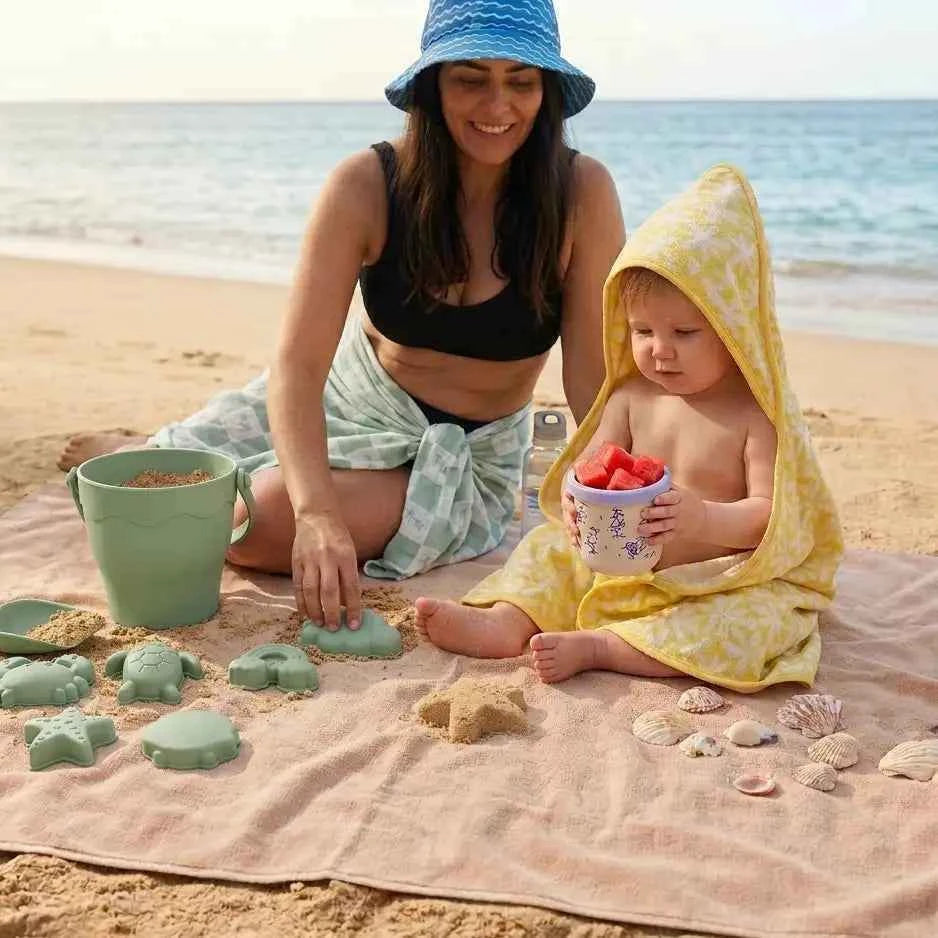 Woman and child on a beach with sand toys and shells