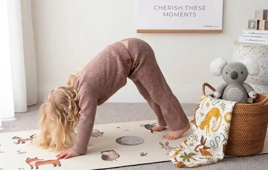 Child playing on a mat with toys and a basket in a room.